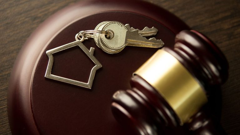 Młotek sędziego licytatora, klucz do drzwi na drewnianym stole. Koncepcja dla sądu, upadłości, podatków, hipoteki, aukcji, wykluczenia lub dziedziczenia nieruchomości